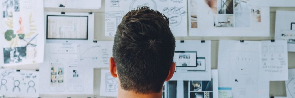 Person looking at a pin board full of drawings and graphics